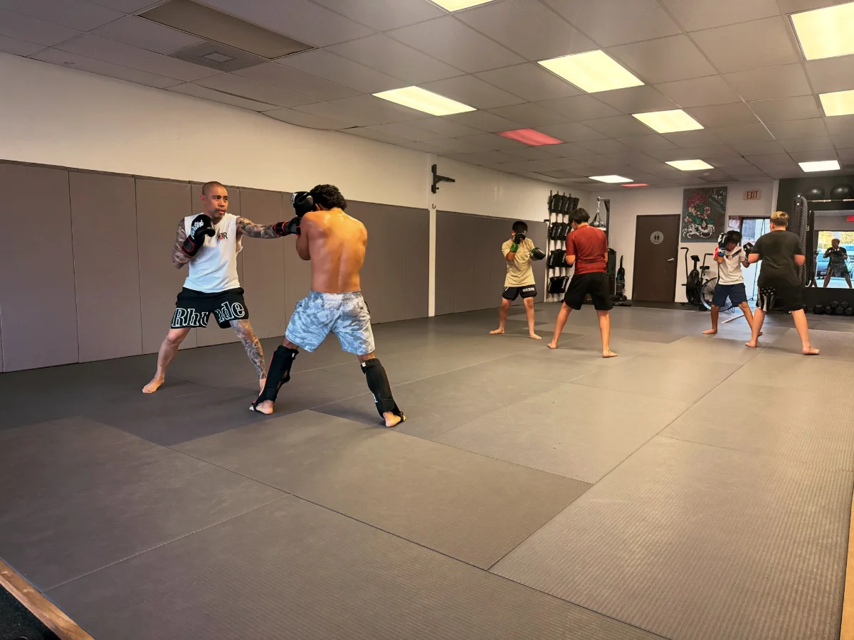 Adult boxing class working combinations on the bag at Kulture BJJ